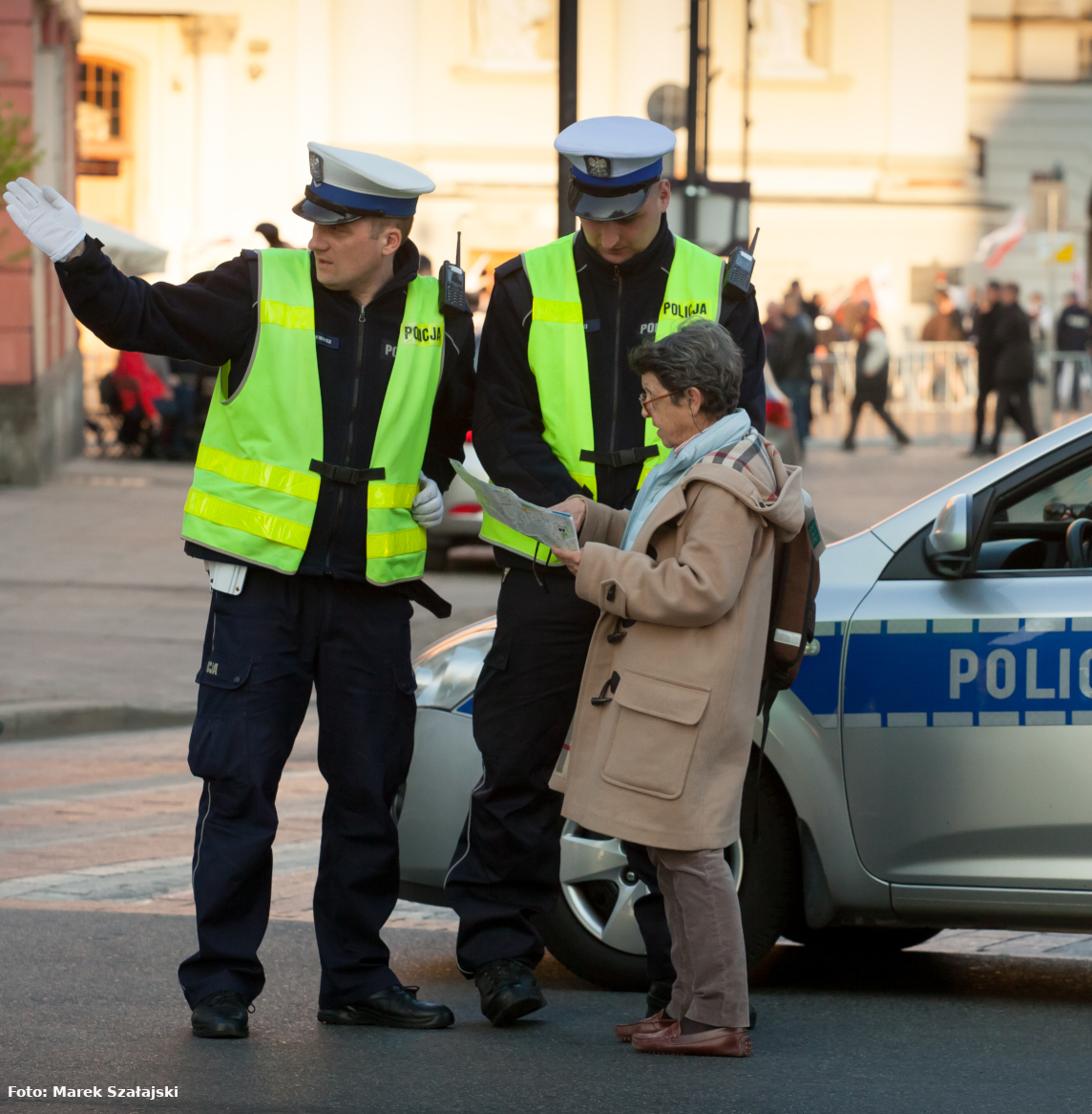 Policjanci Wydziału Ruchu Drogowego KSP wskazują drogę turystce