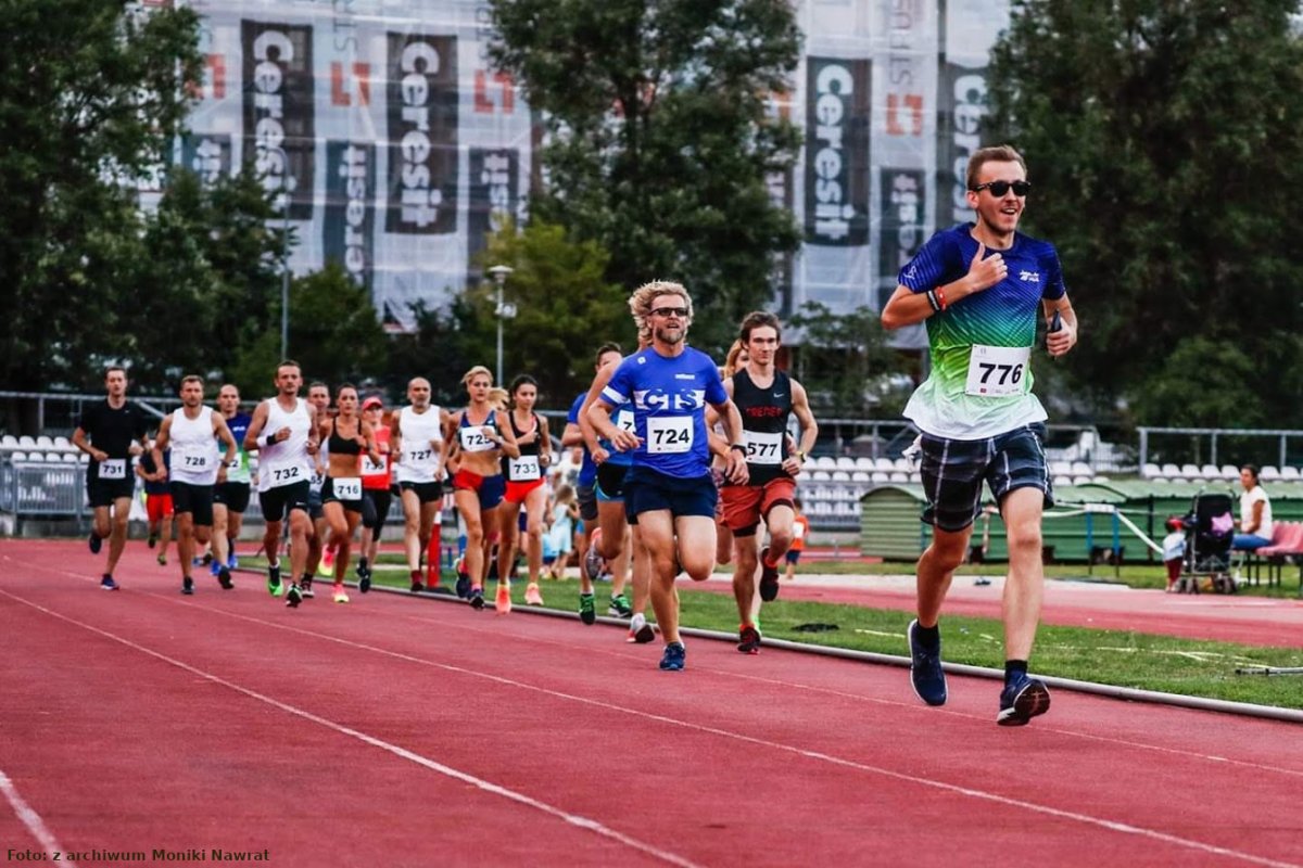 Zdjęcie przedstawia grupę sportowców (kobiety i mężczyzn) biegnących po bieżni.