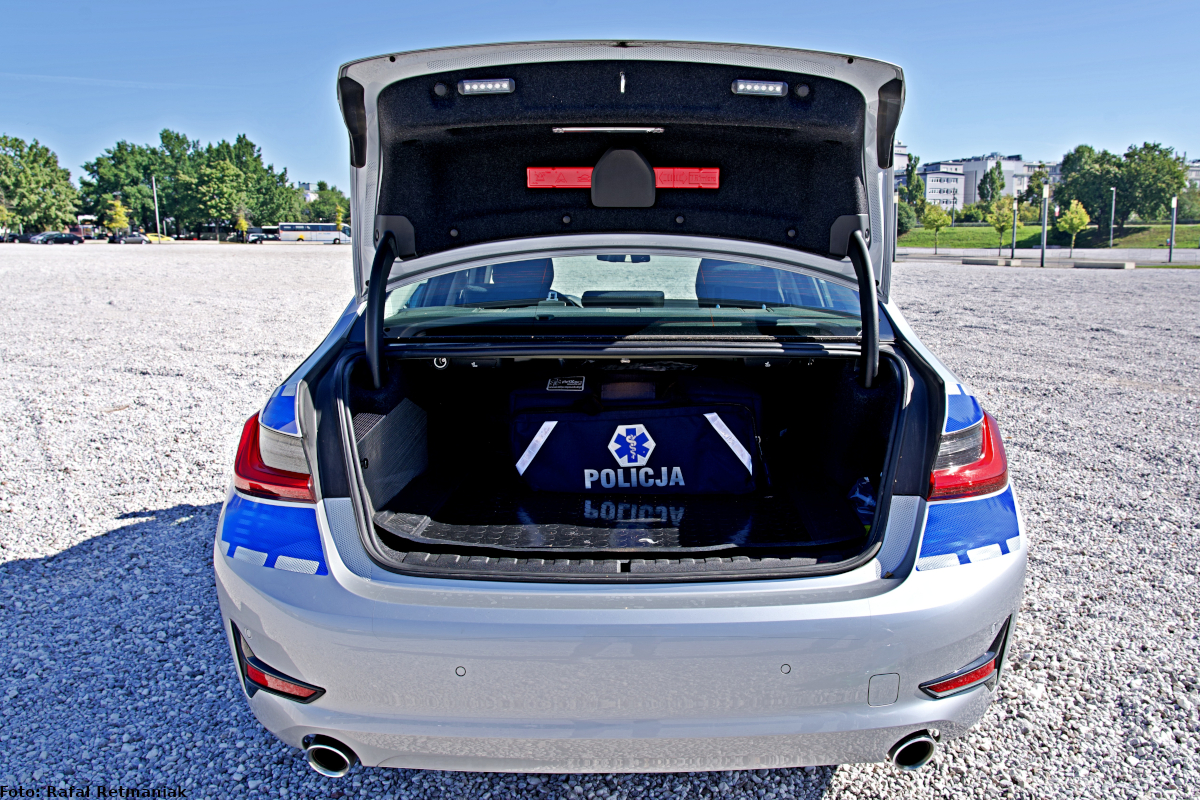 Zdjęcie przedstawia wnętrze bagażnika radiowozu marki BMW,  w środku widać apteczkę z napisem „POLICJA”.
