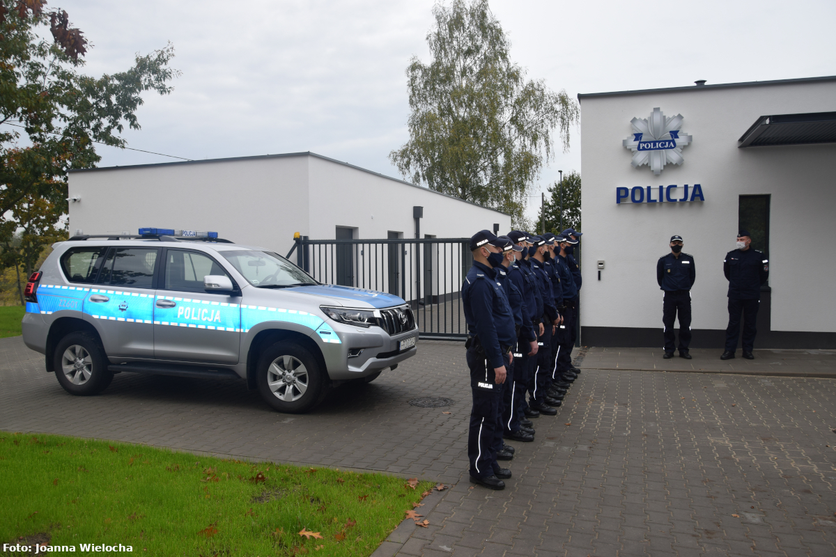 Na zdjęciu, od lewej strony, widać radiowóz typu suv oraz umundurowanych policjantów przed budynkiem Komisariatu Policji w Pomiechówku podczas uroczystego otwarcia.